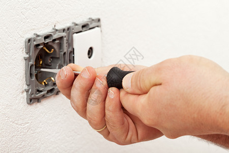 电工手安装墙壁固定装置拧紧螺丝图片