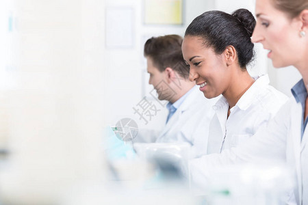一组研究人员在实验室设备工作时微笑着微笑图片