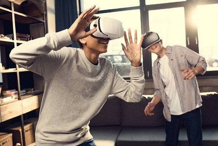 在家里佩戴虚拟现实头盔玩电子游戏概念的青少年图片