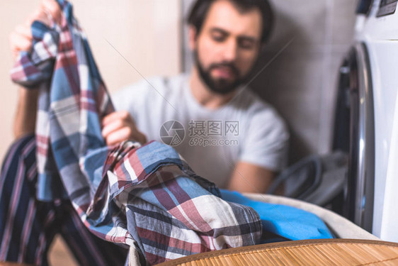 英俊的孤独者在浴室的洗衣机附近洗衣服图片