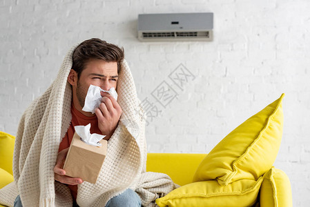 家中坐在空调机下用毯子在毛毯下暖图片