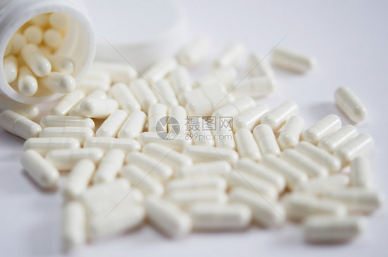 白色背景中从药瓶中溢出的白色药丸图片