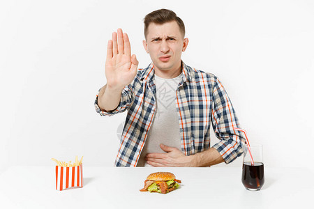 生病的人用手抚摸疼痛腹部胃痛以及汉堡薯条玻璃中的可乐和白色背景隔绝适当的营养或具有复制空间的美国经图片