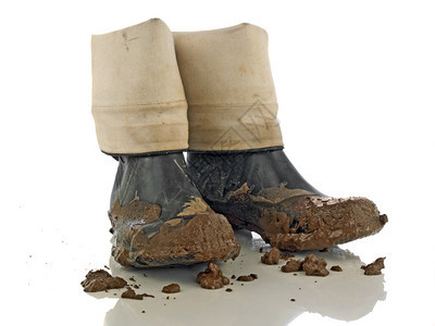 白色反射面上的泥泞橡胶靴图片