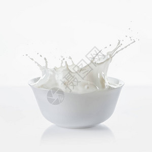 牛奶在白色碗里滴在白色背景上图片