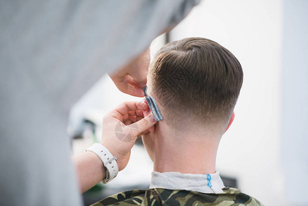 理发师用一把危险的剃须刀剃掉顾客的脖子理发店的男士理发理发师为年轻人图片