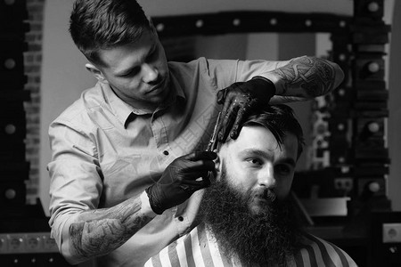 英俊的胡子帅哥正往前看在理发店理发师剪头发的时候图片