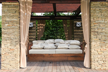 带木沙发和白色枕头的花园砖房背景图片
