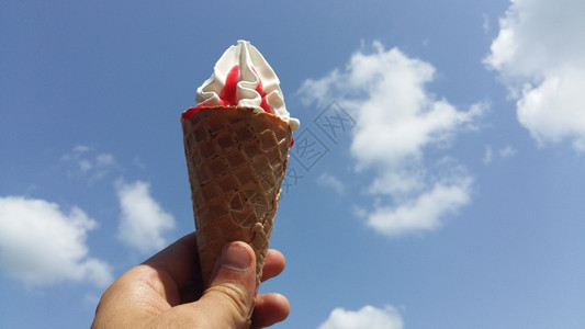 冰淇淋蛋筒顶着炎热的夏日天空背景图片