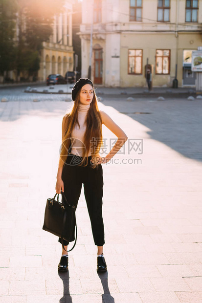 优雅的女孩手里拿着一个黑色的手提包站图片