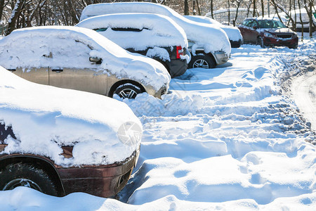 在阳光明媚的冬日莫斯科市停车场上的积雪汽车图片