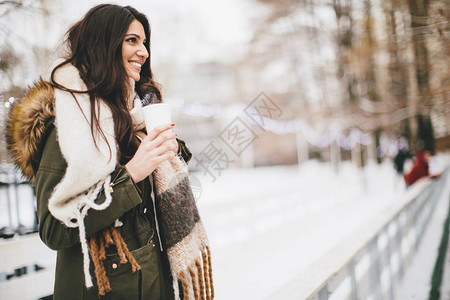 在寒冷的冬天在户外喝一杯热饮的快乐女人背景图片