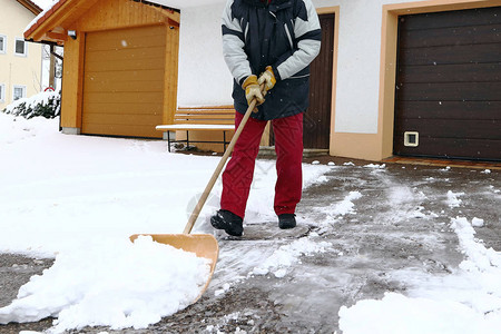 一个男人在车库前铲雪图片