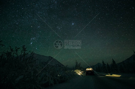 站在冬季路上的汽车和夜晚山上美丽的星图片