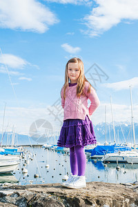 一个可爱小女孩在港口的户外肖像穿着粉红色拖拉衣和紫图片