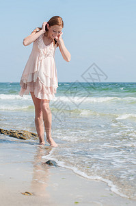 穿着连衣裙的美丽女孩赤脚走在沙滩图片