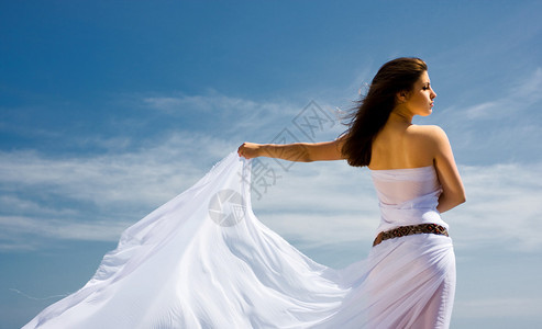 白色织物和天空的年轻美丽的女人图片
