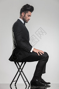 坐在凳子上俯视着一个优雅的年轻人的侧面景色图片