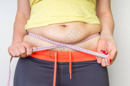 带胶的超重女人测量肚子脂肪图片