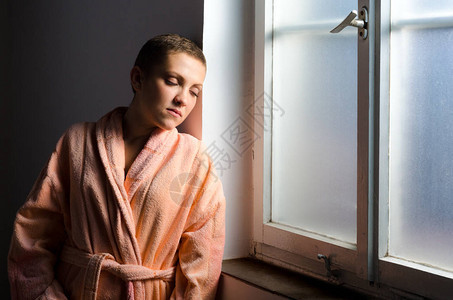 年轻女癌症患者站在医院窗户前图片