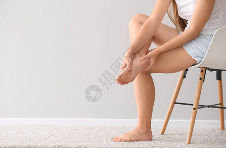 妇女坐在灯墙附近的椅子上时脚部疼图片