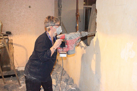 一名妇女使用重工业钻头来击倒和拆除英国Portsmouth住宅的墙壁图片