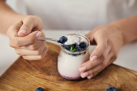 在桌顶用酸奶和新鲜蓝莓在木制剪板上早餐图片