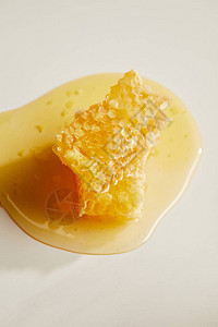 白色桌面上甜蜂蜡和蜂蜜的近景图片