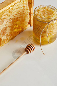 更深的木制蜂蜜装有蜂蜜的玻璃罐子和白色桌面图片