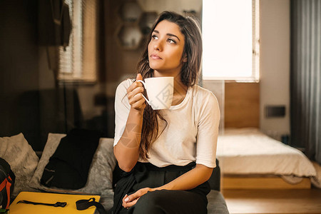 拿着白咖啡杯的女人站在室内图片