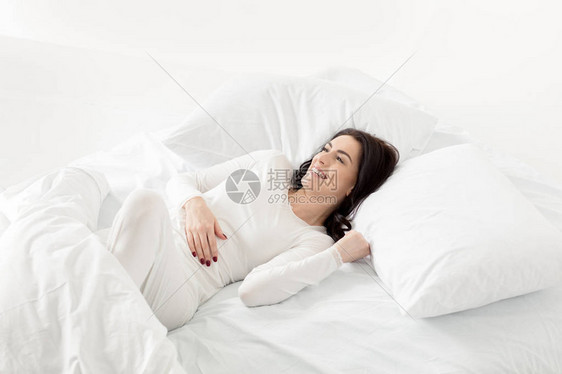 穿着白色睡衣在家中床上醒来的有吸引力的白衣服妇图片