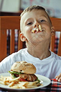 小可爱男孩6岁6岁与汉堡包和薯条做疯狂的脸蛋图片