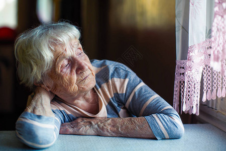 一位老年妇女坐在窗户旁图片