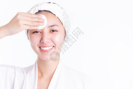 健康的亚洲年轻女用化妆棉卸妆和清洁面部美女沐浴后使用纯棉垫在白色背景上隔离护背景图片
