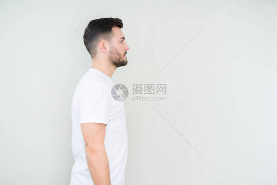 身穿白色短袖圆领汗衫的英俊年轻男子与孤立的背景相望放松姿势和自然面容充图片