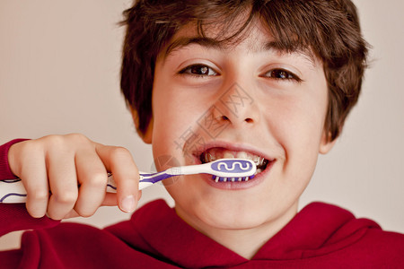 快乐的青少年与牙套和刷牙他的牙齿Ortod图片