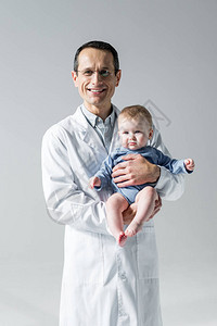 微笑的成年儿科医生抱着小婴儿看着被灰图片