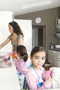 年轻母亲和女儿在家中厨房洗图片