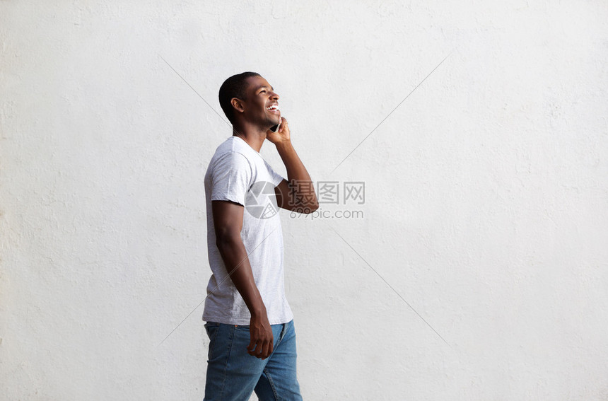 一个微笑着的非裔美国人在手机上行走和说图片