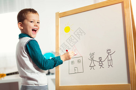 微笑着的可爱小男孩用感知笔在白板上画早图片