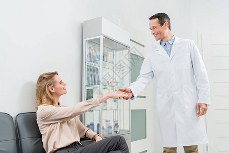 微笑的医生向在现代牙科诊所握手图片