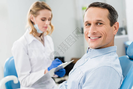 在现代诊所等待的男病人时进行牙科诊断和图片