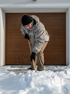 大雪后男子用铲子清理车道上的积雪图片