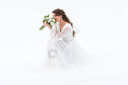 穿着传统礼服的快乐新娘闻着婚礼花束图片