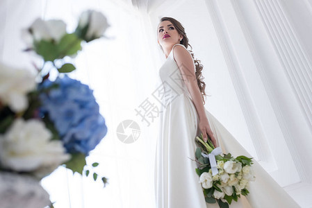 穿着白色礼服和婚礼花束装扮新图片