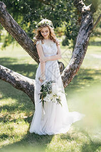 穿着婚纱的美丽年轻新娘拿着花图片