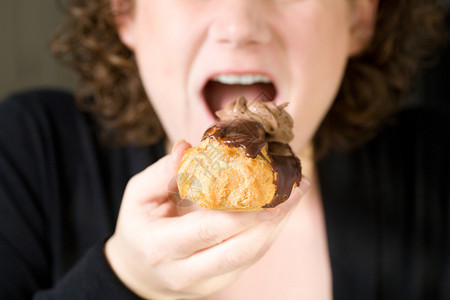 一个女人吃泡芙的特写镜头图片