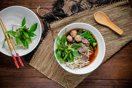 亚洲面条汤配牛肉丸子和新鲜蔬菜在木桌上复古风格街头食品热辣面条汤亚洲图片