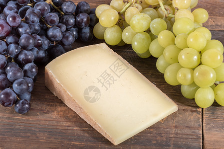 法国伯爵奶酪配黑色和白色葡萄木制背景图片