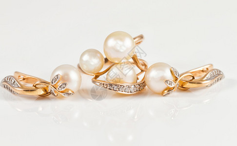 白色反光表面上镶有珍珠的精美黄金首饰套装图片